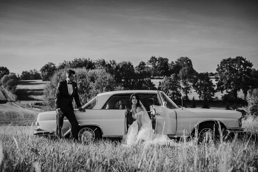 Braut im Hochzeitskleid steigt aus dem Mercedes Oldtimer – charmante Szene der Hochzeit