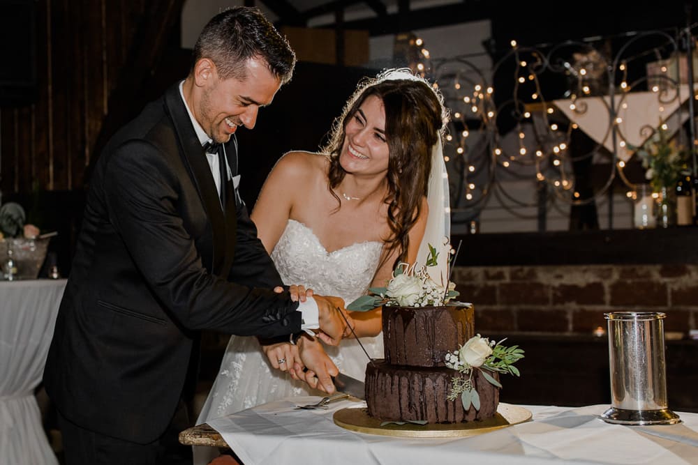 Brautpaar beim Hochzeitstortenanschnitt – glückliche Blicke und emotionale Momente während der Feier