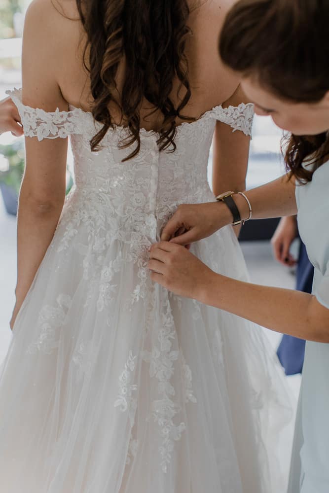 die Trauung Brautjungfern helfen beim Anziehen des Hochzeitskleides – emotionale Unterstützung am Morgen
