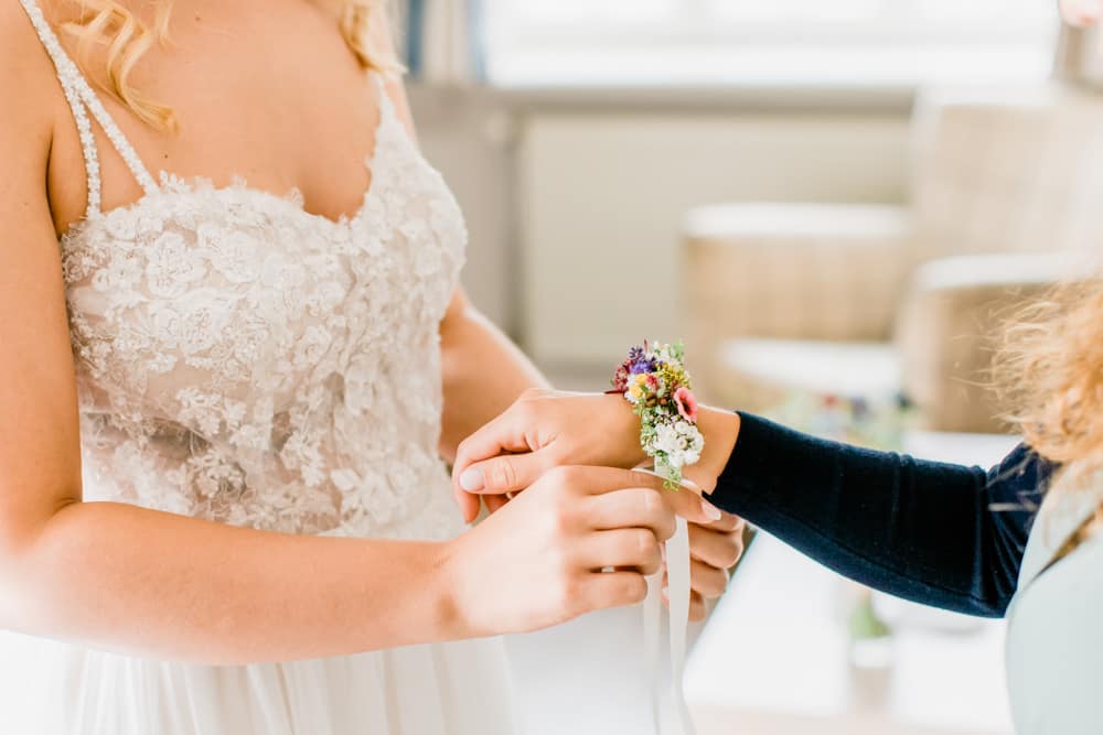 Trauzeugin mit floralem Armband als Geschenk von der Braut. Hochzeitsfotografin für Hochzeitsreportage auf Sylt buchen.