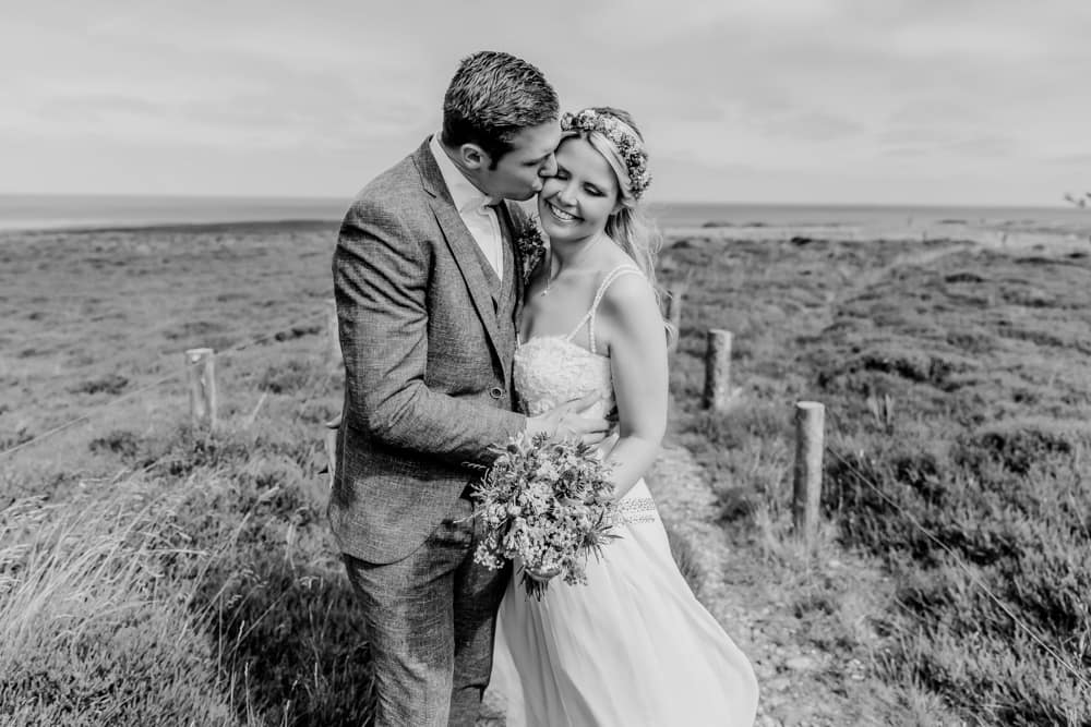 Braut und Bräutigam in den Dünen auf der Insel Sylt. Hochzeitsfotografin für Hochzeitsreportage auf Sylt buchen.