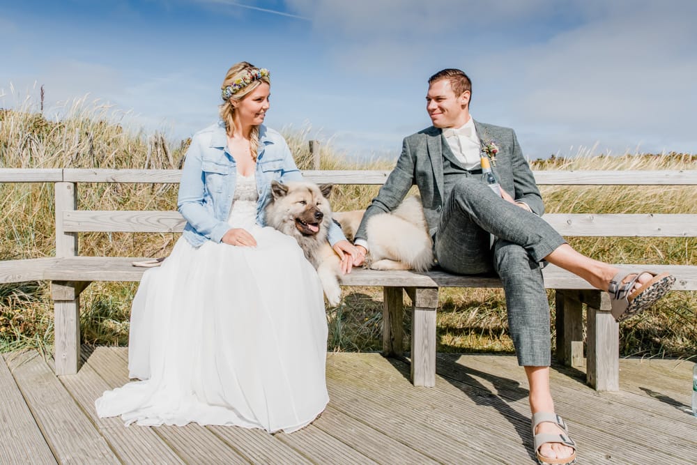 Entspanntes Brautpaar mit Ihrem Hund nach der Trauung im Sylter-Museum. Hochzeitsfotografin für Hochzeitsreportage auf Sylt buchen.